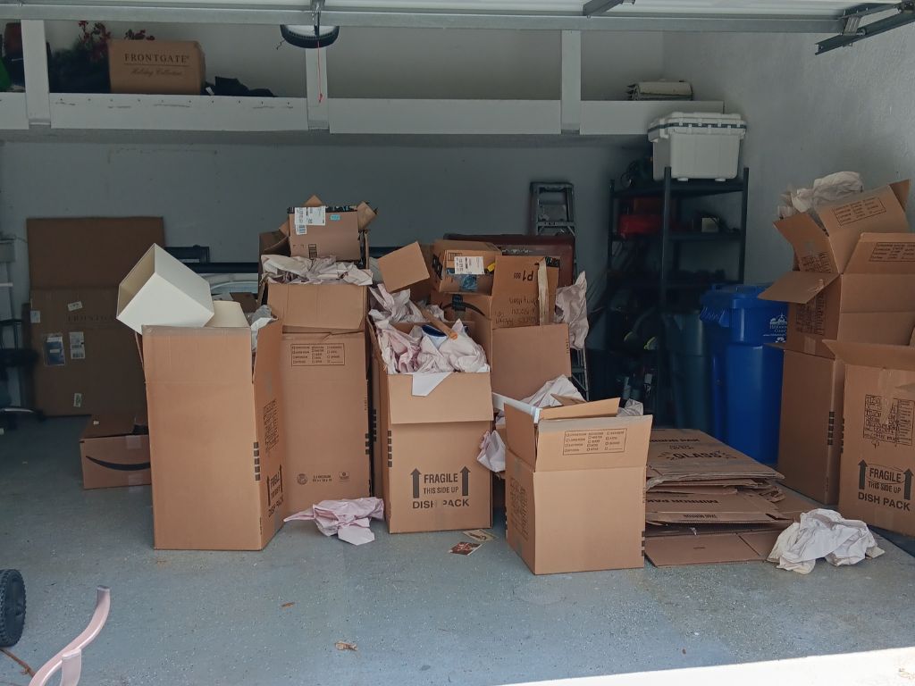 Garage Cleanout Hacks: Get It Done Fast & Efficiently 3 A cluttered garage filled with stacked boxes of junk, with some visible storage items in the background.