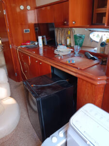 the inside of a boat with a refrigerator, stove, and sink