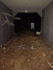 A dark, abandoned-looking building at night with debris and trash on the floor.