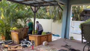 Two men are on a patio beginning the process of dismantling an old hot tub.