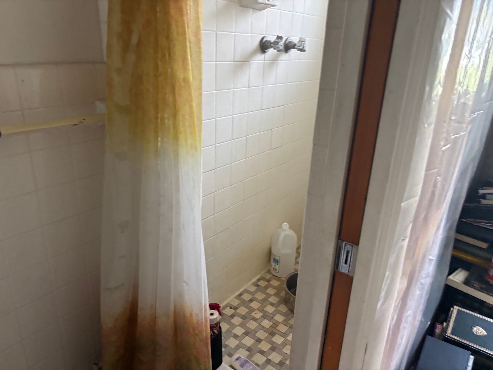 Small bathroom shower with curtain during house cleanout