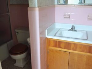 Bathroom sink and vanity in pink tile room awaiting cleanout